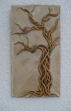 a ceramic wall hanging with two birds perched on it's branches and the tree is made out of clay