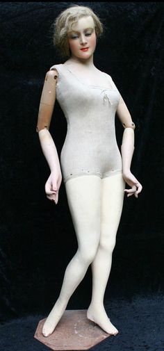 a white mannequin is posed on a black background