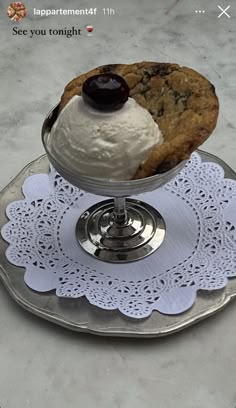 an ice cream sundae is served on a silver platter with doily around it