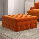 an orange ottoman sitting on top of a rug next to a chair and footstool