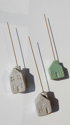 three ceramic houses are sitting on toothpicks in front of a white background and one is green