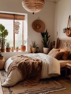 a bed sitting in a bedroom next to a window with potted plants on it