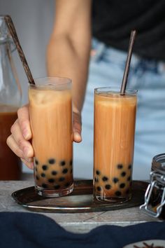 two people are holding their glasses with drinks in them on a tray next to each other