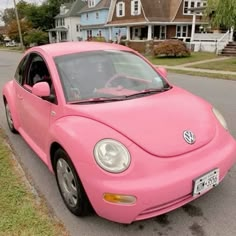 a pink car is parked on the side of the road in front of some houses