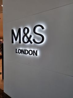 the entrance to m & s london is lit up in black and white with neon letters