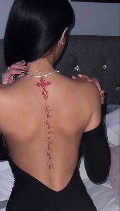 the back of a woman's body with writing on her left shoulder and right arm