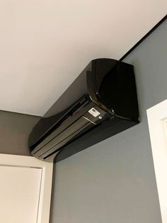 an air conditioner mounted on the side of a wall in a room with gray walls