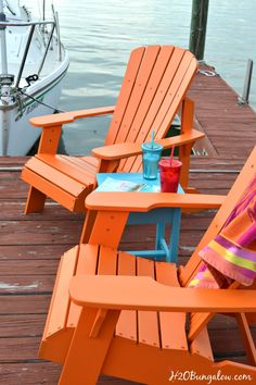 two orange adiron chairs sitting on top of a wooden dock