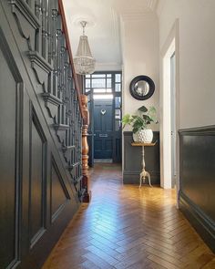 an entry way with wood floors and black painted doors, along with a plant on the floor