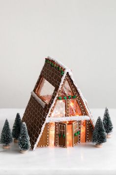 a gingerbread house with christmas decorations on the roof and trees in front of it