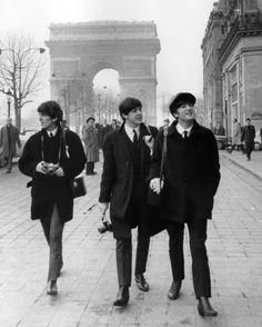 three young men walking down the street in front of the arc de trioe