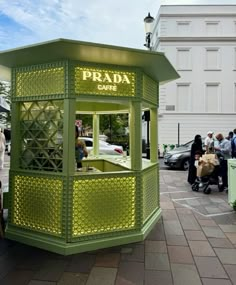 a small green stand with people standing around it