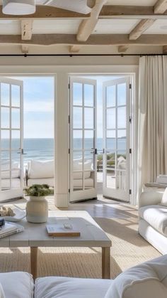 a living room filled with white furniture next to an open door leading to the ocean