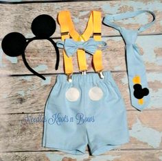 a mickey mouse outfit with suspenders, tie and headband on a wooden surface