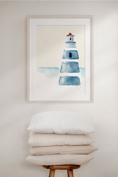 a stack of pillows sitting on top of a wooden stool in front of a white wall