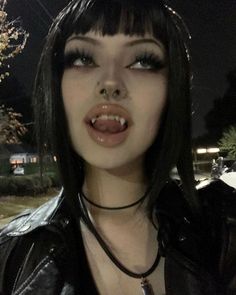 a close up of a person wearing a black leather jacket and piercing on her nose