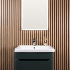 a bathroom sink sitting under a mirror in front of a wooden wallpapered wall