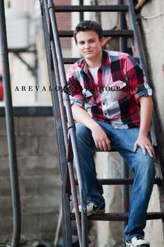 a young man sitting on top of a set of stairs next to a brick wall