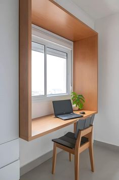 a laptop computer sitting on top of a wooden desk in front of a large window