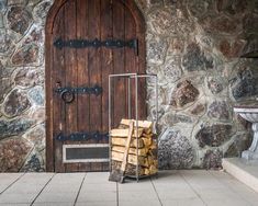 a pile of firewood sitting in front of a stone building next to a door