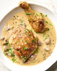 two pieces of meat covered in mushroom gravy on a white plate