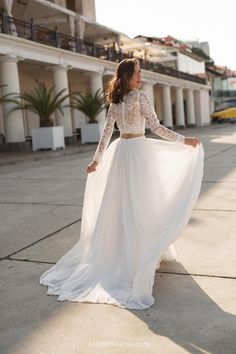 a woman in a white dress is standing on the sidewalk