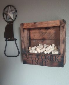 a wooden box filled with wine corks next to a wall mounted star on the wall