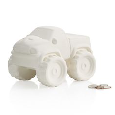 a white plastic toy truck next to a coin