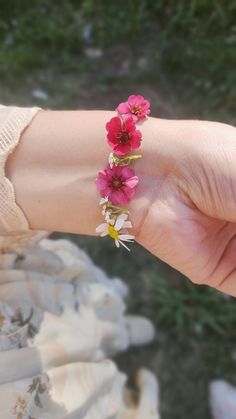 a person's arm with pink flowers on it and green grass in the background