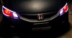 the front end of a honda car with its lights turned on and it's hood up