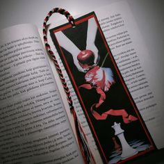 an open book with a red and white design on it, next to a string