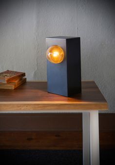 a lamp that is sitting on top of a wooden table next to books and a book