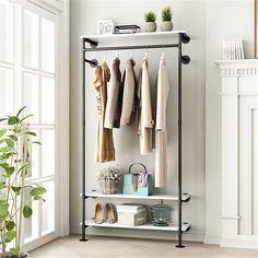 a rack with clothes hanging on it next to a potted plant in a room