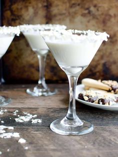 two martini glasses filled with white chocolate and sprinkles on a wooden table