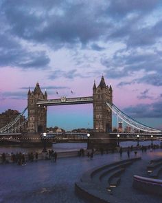 the tower bridge is lit up at dusk