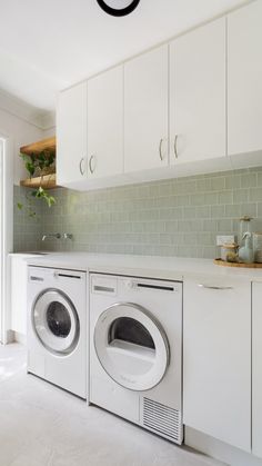 a washer and dryer in a white laundry room with green tiles on the wall