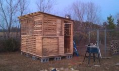 a small wooden outhouse sitting in the middle of a field next to a fence