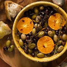 a bowl filled with olives, orange slices and bread