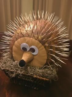 a paper plate hedgehog sitting on top of a wooden table next to a basket