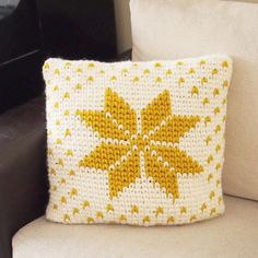 a yellow and white pillow sitting on top of a couch next to a black chair