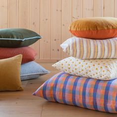 a pile of pillows sitting on top of a wooden floor