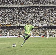 a man kicking a soccer ball on top of a field in front of a crowd