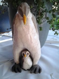 two ceramic birds sitting next to each other in front of a potted planter