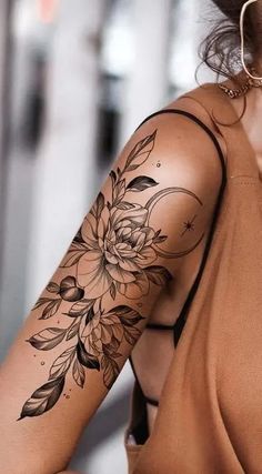 a woman with a flower tattoo on her arm and shoulder is looking at the camera