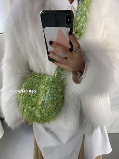 a woman wearing a white fur coat and holding a cell phone in her right hand