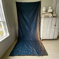 a blue blanket sitting on top of a wooden floor next to a white cabinet and window