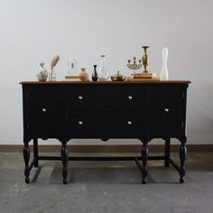 an old dresser with vases and other items on it's top shelf next to a white wall