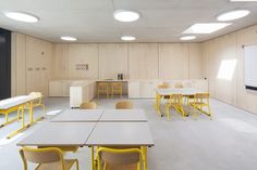 an empty classroom with yellow chairs and desks