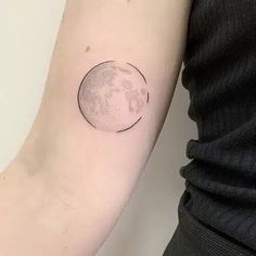 a woman's arm with a small moon tattoo on the left side of her arm