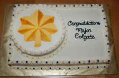 a cake decorated with an orange and white umbrella on top of a wooden table next to a sign that says congratulations major colgate